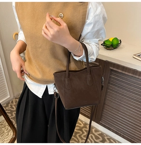 Detail der dunkelbraunen Handtasche aus mattem Leder in einer wohnlichen Umgebung