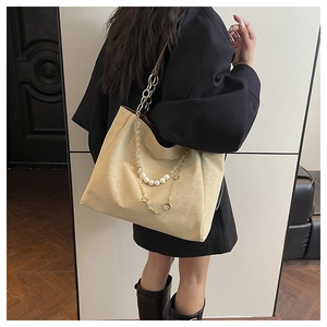 Detail of beige tote bag with multi-layer gold and pearl chain decorations on the side