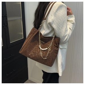 Detail of leopard print tote bag featuring pearl chain and metallic flower pendant