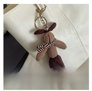 Détail d'un pendentif lapin en tricot marron avec écharpe sur un sac à main en cuir blanc