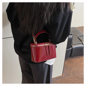 Rear view of red patent leather box bag with gold-tone hardware on model's shoulder