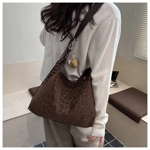 Detail of leopard print tote bag with plush texture and decorative keychain on shoulder strap