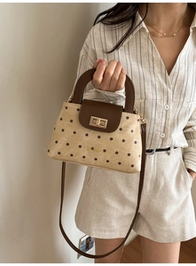 Close-up of vintage polka dot canvas handbag with brown leather flap and gold clasp