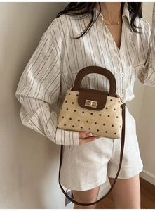 Detailed view of polka dot crossbody bag with golden twist lock and brown handle