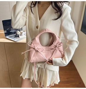 Detailed view of pink bow handbag with fine straps on a desk with lifestyle accessories