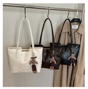Détail de sacs cabas vintage en similicuir crème, marron et noir avec pendentifs lapins