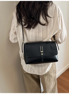 Vue arrière d'un sac bandoulière noir rétro avec boucle dorée porté par un mannequin