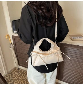 Detail of cream soft leather crossbody bag with decorative bows and pleated texture