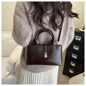 Close-up of vintage chocolate oil leather tote with elegant golden sphere metal clasp
