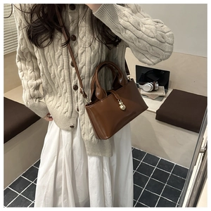 Détail du sac cabas vintage marron avec breloque dorée et bandoulière réglable
