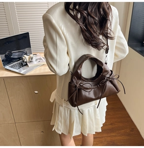 Fashionable dark brown soft leather tote bag with side bows shown on model in a studio