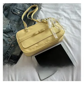 Detail of yellow PU leather bag with lace ribbon, pearl charms and bow decorations