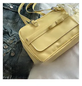 Close-up of cream yellow faux leather handbag featuring lace and pearl accessory charms