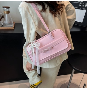 Detail of pink patent leather shoulder bag with a bow accent and pearl lace pendant