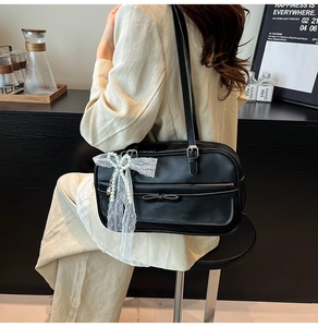 Detail of black Boston bag featuring white lace bow, pearl pendant and leather bow accents