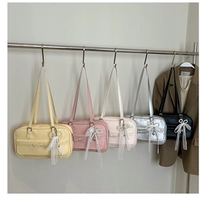 Detail of five colorful leather shoulder bags with lace bow charms and decorative front bows