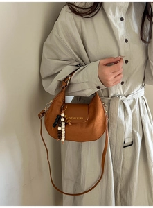 Detail of vintage brown hobo bag featuring suede patchwork and a wooden bead charm strap