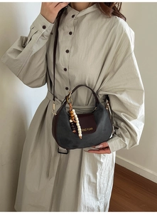 Detail view of a vintage shoulder bag with grey suede and brown leather on model