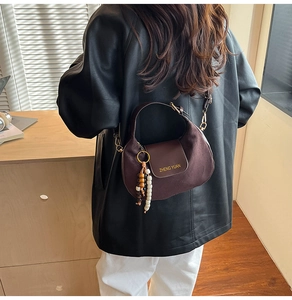Detail of dark brown crescent saddle bag with beaded tassel and adjustable strap