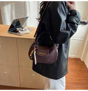 Detail of dark brown suede crescent bag with artistic beads and a leather flap