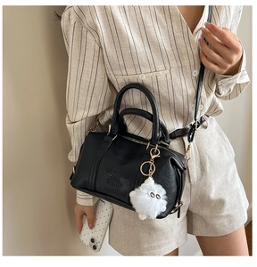 Detail of black Boston style handbag with Fashion Air Paris embossing and plush monster charm