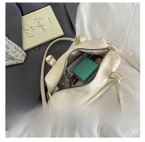 Top view of cream handbag interior showing spacious capacity with cosmetics and green box