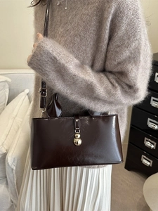 Vintage dark brown oil leather tote bag with gold buckle shown on a female model