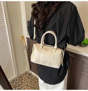 Close-up of cream Boston bag with lychee grain texture and gold hardware detail