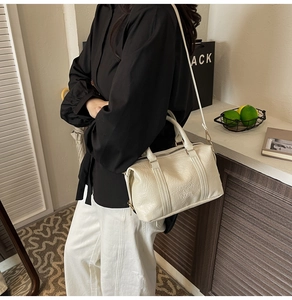 Detail of creamy white Boston bag with embossed FASHION AIR PARIS text and pleated texture