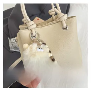 Detail of beige lychee leather tote with rope knot handle and monster plush charm