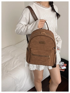 Détail du sac à dos vintage marron avec motifs de cœurs gravés et logo en métal