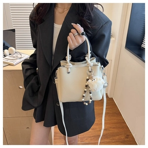 Detail view of cream white textured leather tote bag with a cute plush lamb pendant charm