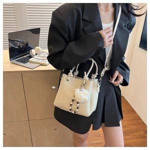 Chic cream leather tote with plush monster charm on a minimalist desk background
