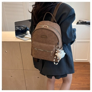 Détail du sac à dos marron vintage avec ours en relief, plaque et breloque en peluche