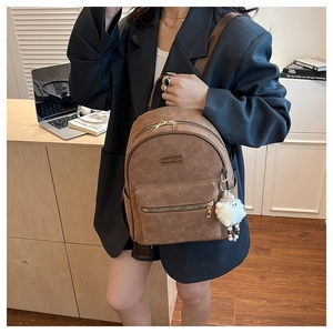 Gros plan du sac à dos vintage marron avec motifs en relief et pendentif en peluche
