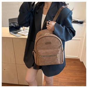Détail du sac à dos marron vintage avec gaufrage de dessin animé et logo en métal doré
