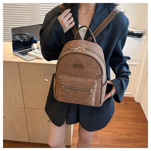 Détail du sac à dos en simili daim marron avec motifs de dessins animés et zips dorés