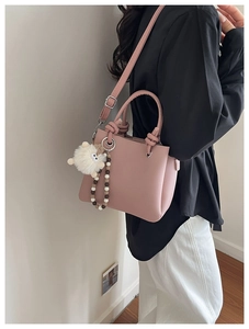 Pink lychee texture tote with plush sheep charm and wood bead detail on model