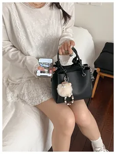 Detail of black lychee leather tote with silver rings and white sheep plush charm