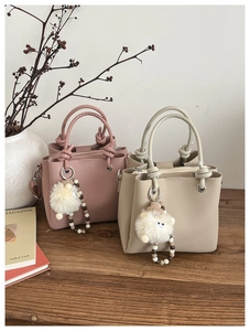 Detailed view of lychee leather tote bags with knot handles and plush sheep pendants