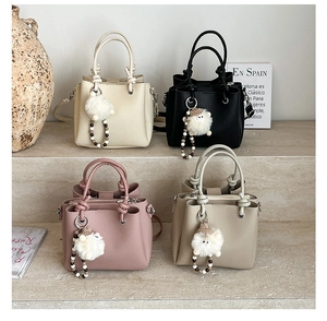 Detail view of four crossbody bucket bags in various colors with plush lamb charms