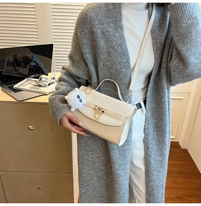 Chique crème PU crossbodytas met goudkleurig slot en pluche hanger op een outfit