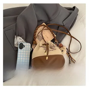 Detailed view of cream and brown bucket bag with twisted handle and bear pendant