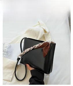 Détail d'un sac à main noir en simili cuir avec foulard en soie floral sur la poignée