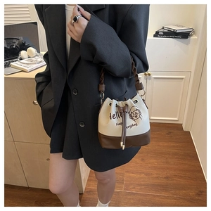 Close-up of embroidered bucket bag with woven handle and cartoon cat print detail