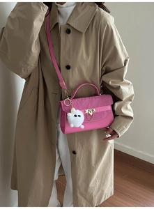Detail van roze crossbodytas met geplooide flap, gouden sluiting en monsterbedeltje