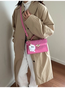 Roze leren crossbodytas met gouden kettinggesp en een witte pluizige pompon bedel