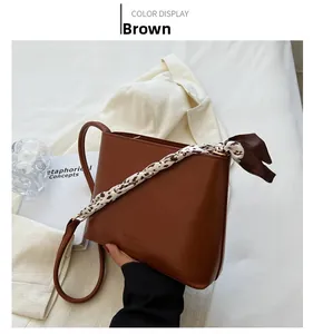 Détail d'un sac à bandoulière en similicuir marron avec foulard en soie et sangle réglable