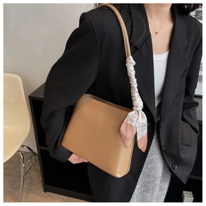 Gros plan du sac à bandoulière en cuir marron avec un foulard décoratif en soie