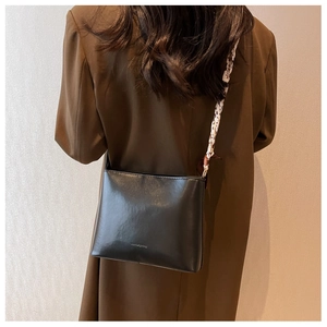 Détail du sac bandoulière noir avec un foulard en soie léopard chic attaché à la bandoulière